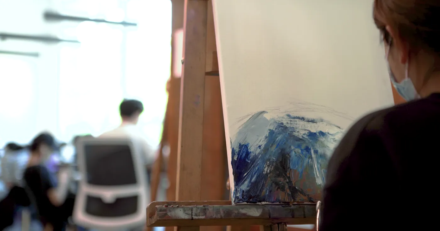 Abstract acrylic study on an easel with a drawing class underway behind it